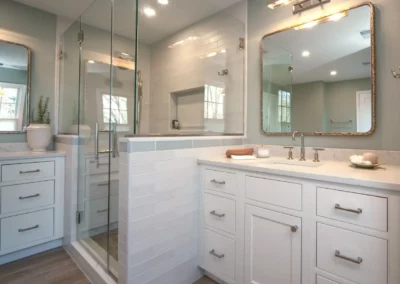 Updated bathroom with white cabinetry and a glass shower and fun rounded rectangle mirror