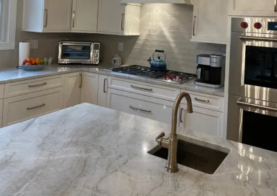 Up close view of a kitchen island with a grey/white marbled surface and a sink