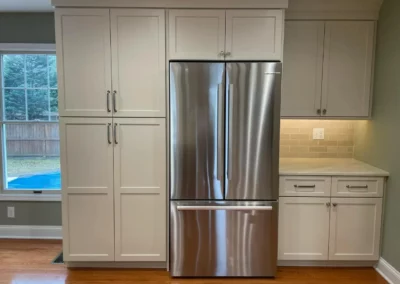 Updated white cabinets in a kitchen with a stainless steel fridge