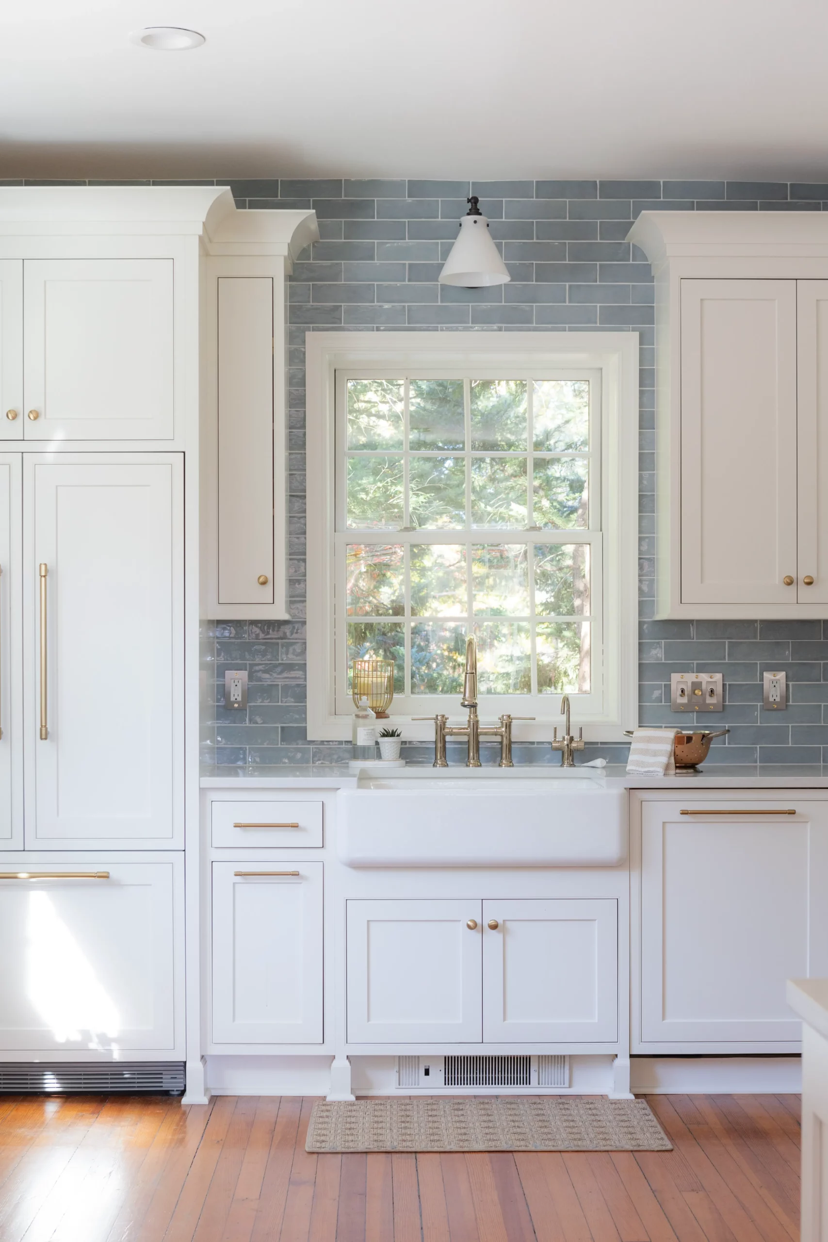 West Haven, Maryland Kitchen Renovation with Ivory Stone Interiors View of Window and Kitchen Sink with white cabinets and brass handles and blue tile